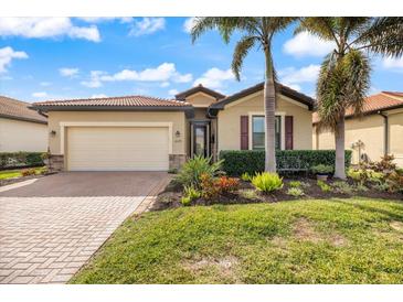 Charming single-story home with a manicured lawn and a brick-paved driveway leading to a two-car garage at 10379 Medjool Dr, Venice, FL 34293
