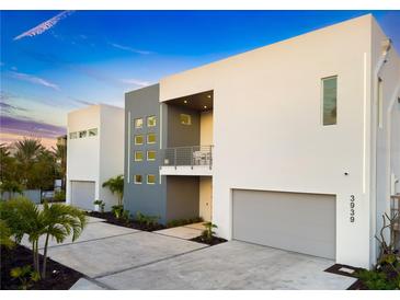 Modern two-story home with a gray and white facade, balcony, gray garage door, and landscaped front yard at 3939 Higel Ave, Sarasota, FL 34242