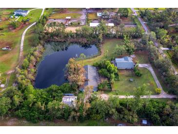 Expansive aerial view of a serene property featuring a large pond, lush greenery, and charming homes at 5645 Churchill Downs Rd, Sarasota, FL 34241