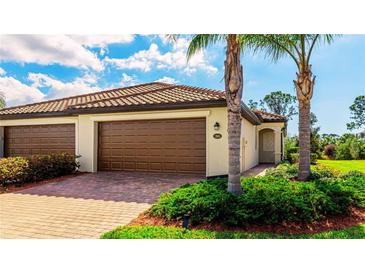 Charming home featuring a tile roof, a brick driveway, a two-car garage, and lush landscaping at 12651 Garibaldi Ln, Venice, FL 34293