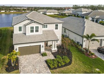 Beautiful two-story home with a gray tiled roof, brick driveway, and well-maintained landscaping at 3704 Wild Blossom Pl, Parrish, FL 34219