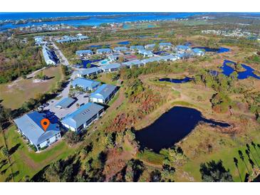 An aerial view of a condo community with ponds, tennis courts, and access to bay views at 6800 Placida Rd # 2017, Englewood, FL 34224