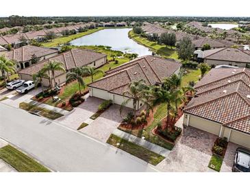 Beautiful aerial view of tile-roofed homes in a well-maintained community with lush landscaping and serene lake views at 20289 Benissimo Dr, Venice, FL 34293