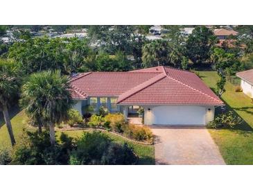 Charming single-story home featuring a red tile roof, lush landscaping, and an attached two-car garage at 395 W Rossetti Dr, Nokomis, FL 34275