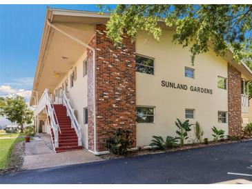 Charming condo exterior with brick detail and access stairs in a lush landscape at Sunland Gardens at 3751 S School Ave # 11, Sarasota, FL 34239