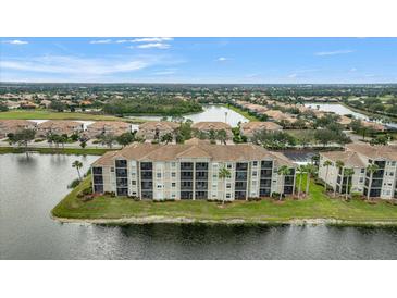 Stunning aerial view of a lakeside condo community with lush landscaping and beautiful water views at 7911 Grand Estuary Trl # 106, Bradenton, FL 34212