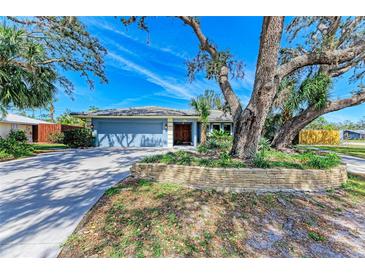 Charming single-story blue home with a large front yard and mature landscaping at 2299 Riverwood Ct, Sarasota, FL 34231