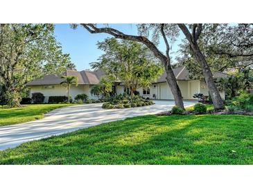 Stunning ranch-style home featuring a circular driveway, lush landscaping, and mature trees providing ample shade at 3178 Dick Wilson Dr, Sarasota, FL 34240