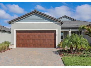 Charming home featuring a well-maintained lawn, a large garage, and a beautiful paver driveway at 12525 Lily Quartz Loop, Parrish, FL 34219