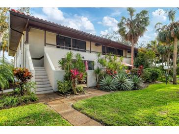 Two-story condo featuring lush landscaping, a brown tile roof, and a private front entrance with stairs at 3500 El Conquistador Pkwy # 149, Bradenton, FL 34210