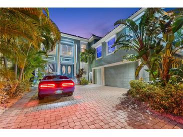 Stunning two-story home featuring lush tropical landscaping, a paver driveway, and a three-car garage at 1215 Acappella Ln, Apollo Beach, FL 33572