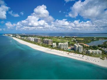 Breathtaking aerial view showcasing a beachfront condo community with pristine sands and turquoise waters at 240 Sands Point Rd # 4201, Longboat Key, FL 34228