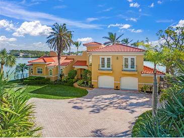 Stunning Mediterranean-style home with a red tile roof, lush landscaping, and paver driveway leading to a two-car garage at 929 Casey Cove Dr, Nokomis, FL 34275