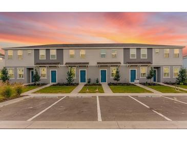 Well-maintained two-story townhomes with blue front doors, landscaping, and ample parking spaces at 16606 San Nicola Pl, Lakewood Ranch, FL 34211