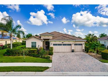 Charming single-story home featuring a three-car garage, terracotta tile roof, and lush tropical landscaping at 6630 Horned Owl Pl, Sarasota, FL 34241