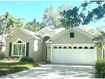 Charming single-story home featuring a white garage door and beautifully landscaped front yard at 96 Tall Trees Ct, Sarasota, FL 34232