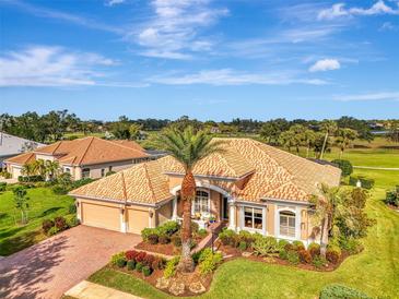 Stunning aerial view of a home with a tile roof, lush landscaping, and a well-manicured lawn at 124 Ventana Way, Venice, FL 34292