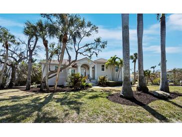 Beautiful exterior view of a single-Gathering home with mature trees, lush landscaping, and a well-manicured lawn at 3540 Bayou Cir, Longboat Key, FL 34228