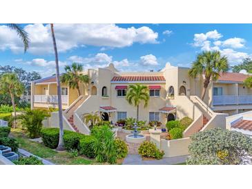 Charming condo building with lush landscaping, a fountain, and inviting entrances under a sunny, partly cloudy sky at 6101 34Th W St # 17C, Bradenton, FL 34210