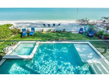 Aerial view of a backyard pool and hot tub with beach access and lounge seating at 915 N Shore Dr, Anna Maria, FL 34216