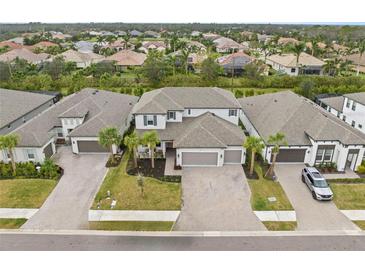 An aerial view shows the home and surrounding neighborhood with paved driveways and tropical landscaping at 1012 Fernleaf Run, Bradenton, FL 34212