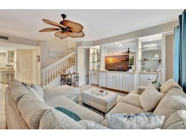 Inviting living room features a decorative ceiling fan, plush sectional sofa, and custom built-in shelving at 5972 Giardino Ln, Sarasota, FL 34232