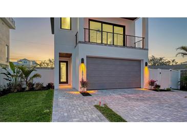 Modern two-story home featuring a spacious garage, stylish balcony, brick driveway, and inviting front entrance at sunset at 1214 Gulf Blvd, Englewood, FL 34223