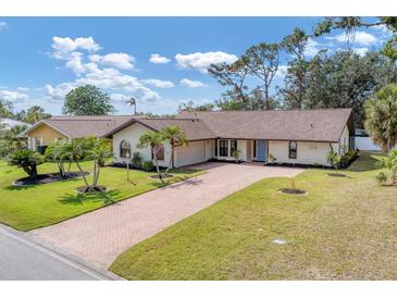 Charming single-story home with a brick driveway, lush lawn, and manicured landscaping at 1219 Sleepy Hollow Rd, Venice, FL 34285