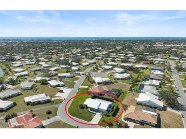 Wide aerial shot showcasing a community of single-Gathering homes with manicured lawns and a glimpse of the ocean in the distance at 308 Matisse E Cir, Nokomis, FL 34275