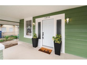 Inviting front door with side windows, potted plants, and 'hello' mat on the covered porch at 1010 E Lake Ave, Tampa, FL 33605