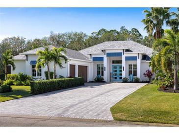 Bright exterior showcasing a pristine white facade, vibrant blue accents and a paver driveway at 3407 155Th E Ave, Parrish, FL 34219
