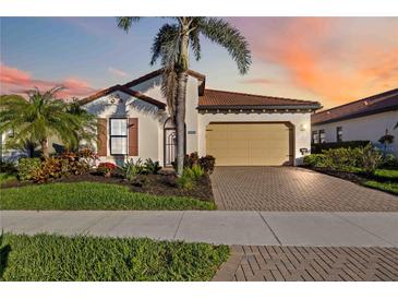Charming single-story home with a two-car garage, tile roof, and lush tropical landscaping at 23703 Waverly Cir, Venice, FL 34293