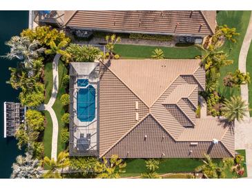 Stunning aerial view of a home with a screened pool, lush landscaping, and a tile roof at 579 Fore Dr, Bradenton, FL 34208