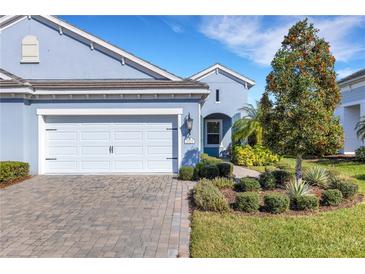 Charming blue single-Gathering home showcasing a well-maintained lawn and a two-car garage with brick driveway at 3325 Azurite Way, Bradenton, FL 34211