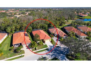 Aerial view of a home with a clay tile roof situated on a verdant, landscaped lot in a scenic residential community at 735 Foggy Morn Ln, Bradenton, FL 34212