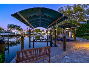 Covered boat dock with lift on a calm waterway provides direct water access and scenic views at 121 Holly Ave, Sarasota, FL 34243