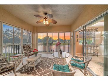 Enclosed lanai with comfortable seating, ceiling fan, and sunset views over the water at 6334 Grand Oak Cir # 201, Bradenton, FL 34203