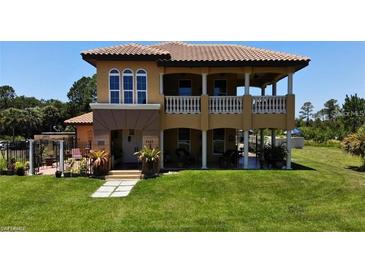 Two-story home with a tile roof, balcony, manicured lawn, and lush landscaping at 8059 Strasse Blvd, Punta Gorda, FL 33982