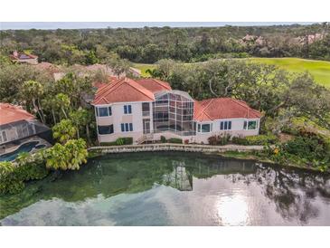 Beautiful waterfront home with a red tile roof, screened lanai and lush landscaping at 7460 Monte Verde, Sarasota, FL 34238