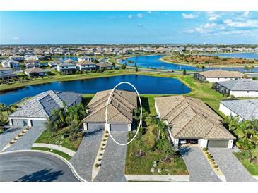 An aerial view of a neighborhood featuring waterways and houses with tile roofs and paver driveways on well manicured lots at 15917 Clear Skies Pl, Lakewood Ranch, FL 34211