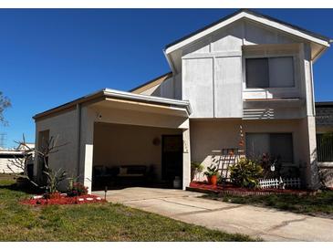 Charming two-story home featuring an open carport, manicured lawn, and a beautifully landscaped yard at 2566 Forest Run Ct, Clearwater, FL 33761