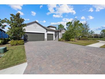 Beautiful single-Gathering home with an attached garage, lush landscaping, and a brick driveway at 12029 Perennial Pl, Lakewood Ranch, FL 34211