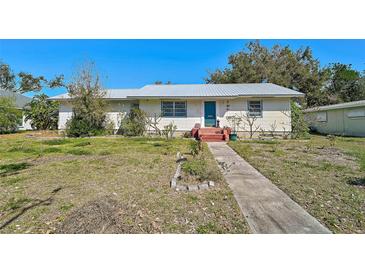 Charming single-story home featuring a metal roof, a blue front door, and a simple landscaped yard at 2302 8Th W Ave, Bradenton, FL 34205