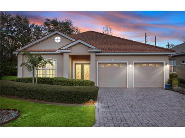 Charming single-story home with a well-manicured lawn, brick driveway and tile roof at sunset at 6211 Skyward Ct, Bradenton, FL 34203