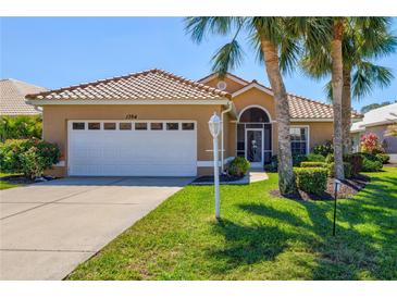 Charming home with a well-manicured lawn and mature palm trees in a desirable neighborhood at 1364 Berkshire Ct, Venice, FL 34292