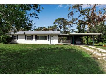 Charming single-story home featuring a well-maintained lawn, a carport, and a vibrant landscape at 5808 13Th Street E Ct, Bradenton, FL 34203