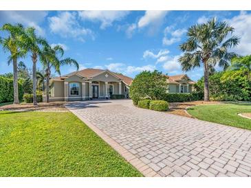 Charming home with a paver driveway, mature trees, and lush landscaping at 3336 Lakeside Cir, Parrish, FL 34219