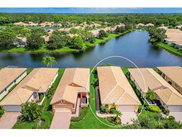 Aerial view of a beautiful single Gathering home with tile roof and lush landscaping on lakefront property at 4244 Reflections Pkwy, Sarasota, FL 34233