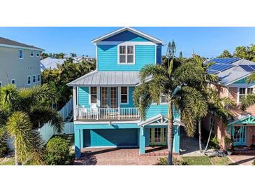 Exterior of bright blue two-story coastal home with balcony, garage, and tropical landscaping at 312 61St St # A, Holmes Beach, FL 34217