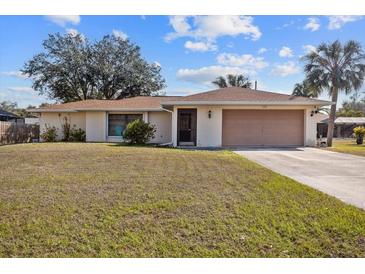 Charming single-story home with a well-maintained lawn, attached garage, and mature trees at 1058 Bounds St, Port Charlotte, FL 33952